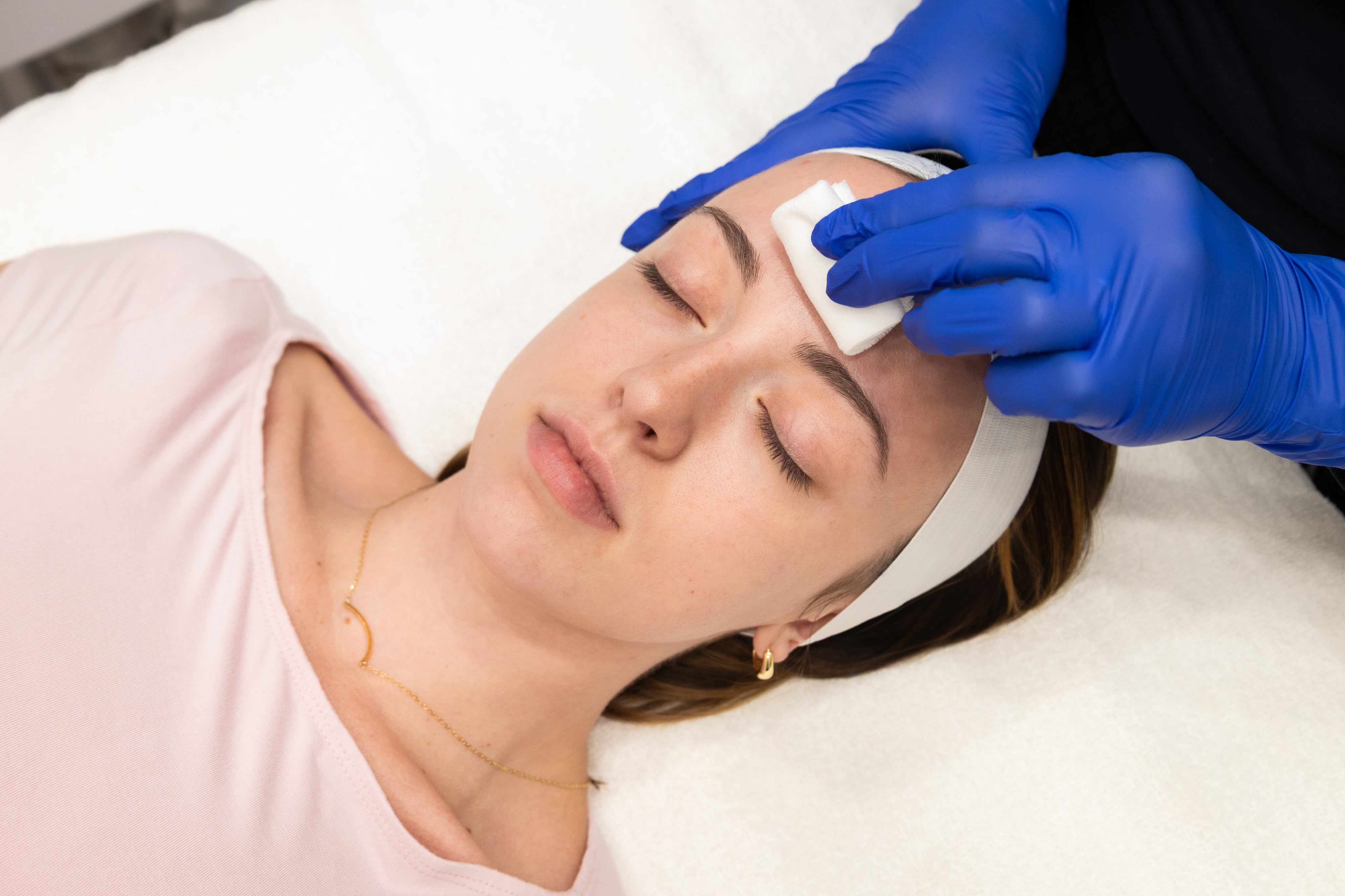 Person receiving a facial treatment with gloves on hands