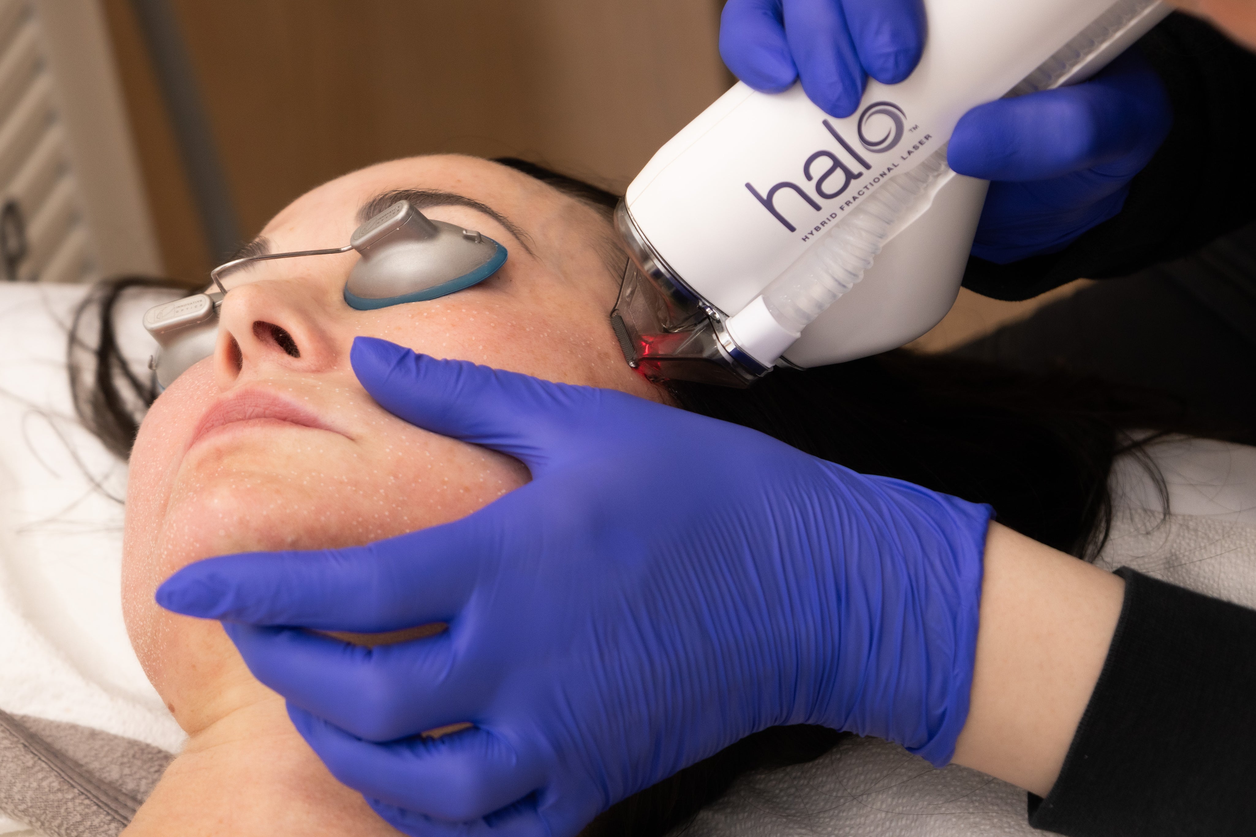 Person receiving a facial treatment with a device labeled 'halo' on a clinical setting.