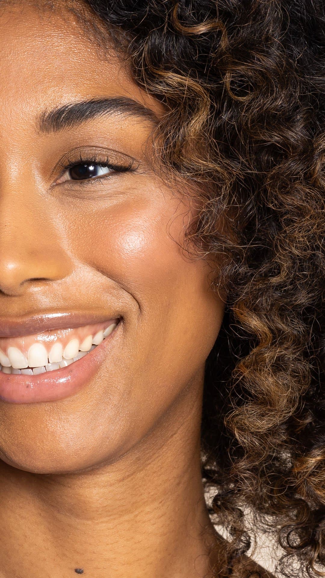 Close-up of a woman with a warm smile and curly hair.