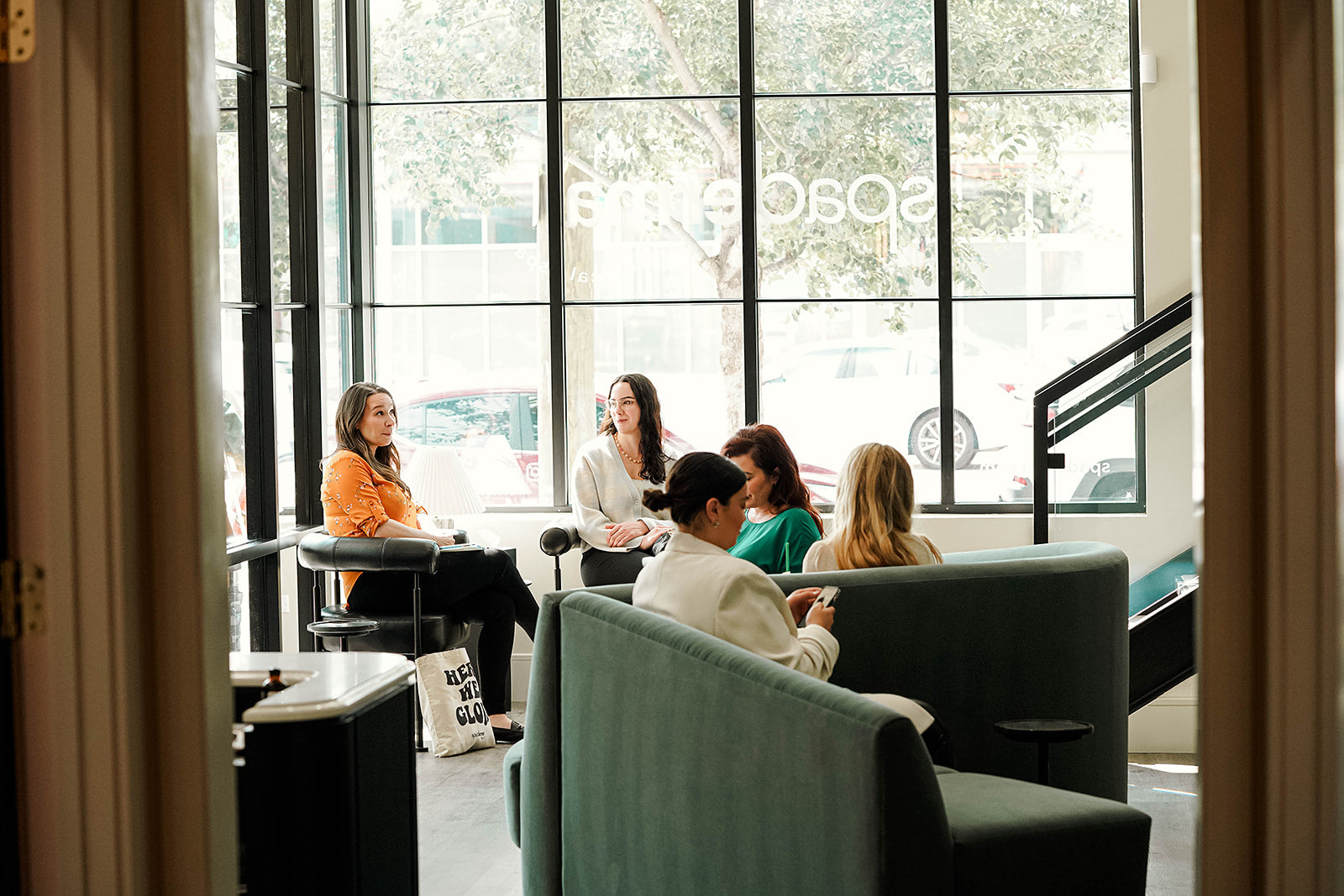 Group of people sitting in a modern spa setting with large windows.