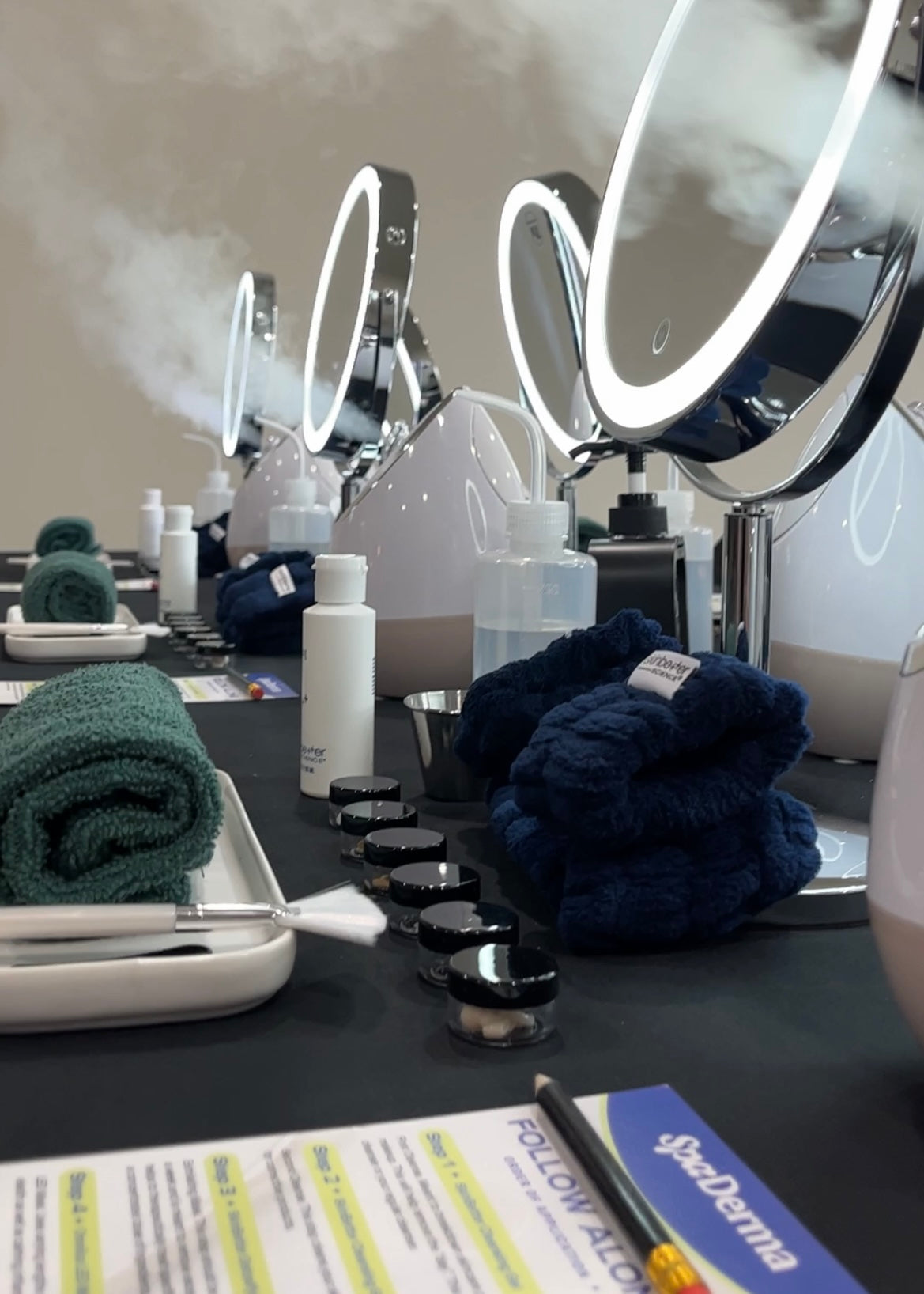 Skincare station with mirrors, towels, and a follow along on a table.