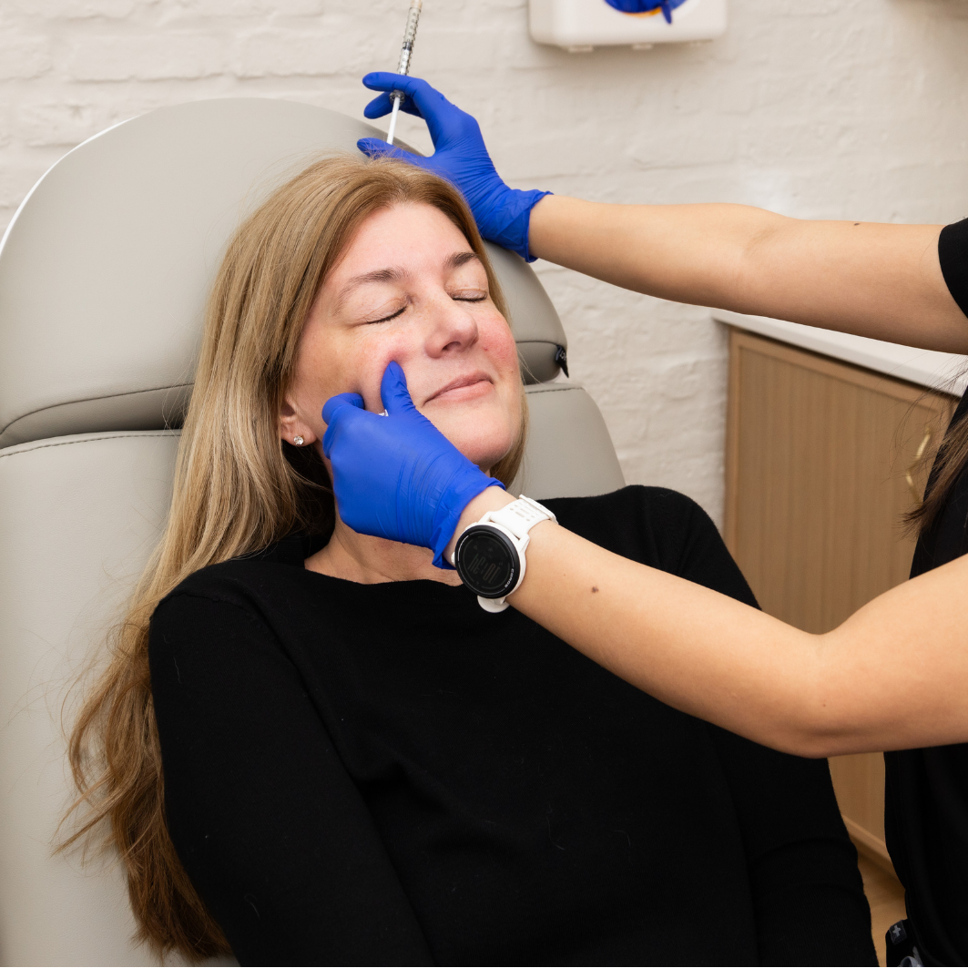 Woman receiving a facial injection from a professional in a clinical setting.