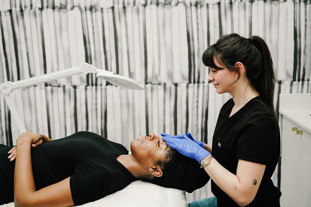 Person receiving a facial treatment from a professional in a clinical setting.