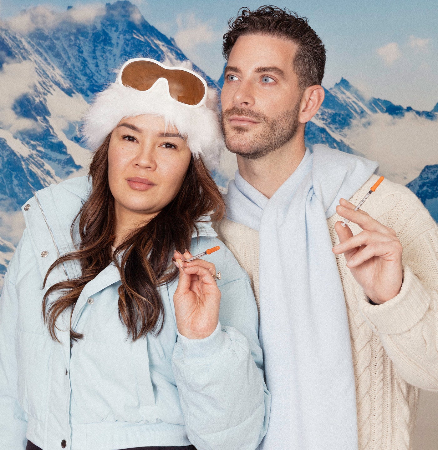 Two people in light jackets with a mountainous background