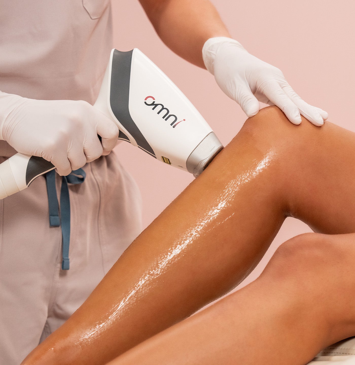 Person receiving laser hair removal treatment on leg with 'omni' device.