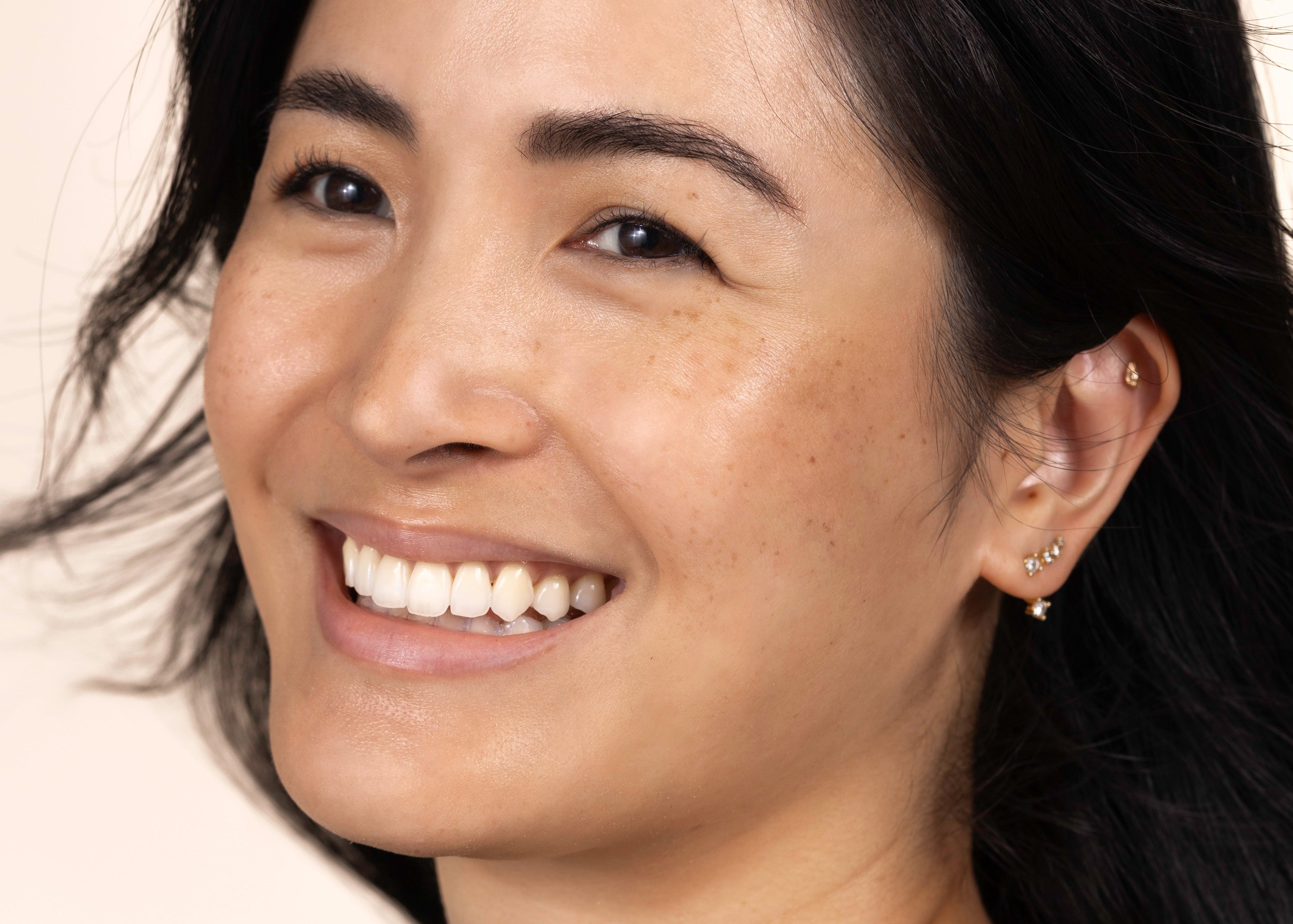 Woman with dark hair and a black top against a plain background